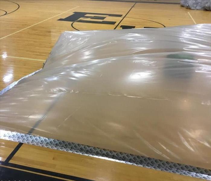 gym floor with plastic containment over wet area