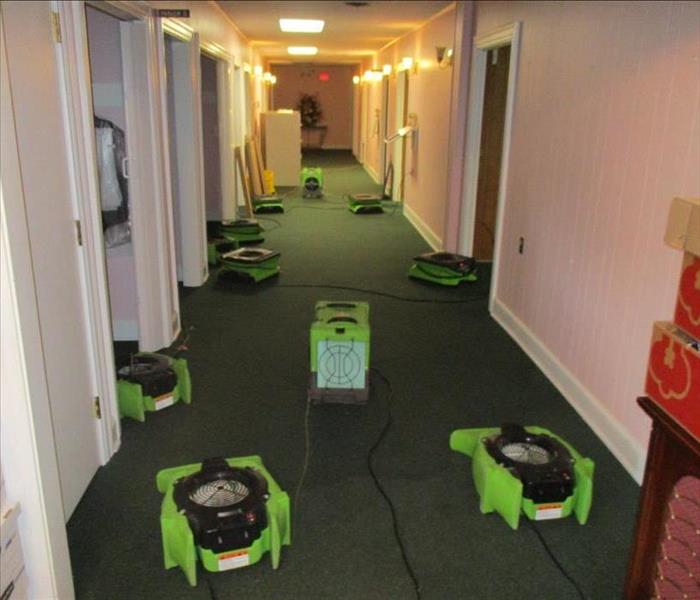 fans and dehumidifier set up in hallway with wet carpet