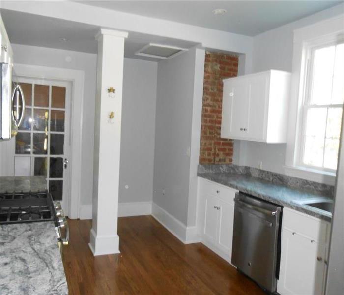 same kitchen with new hardwood floors and fresh coat of white paint on cabinets and walls