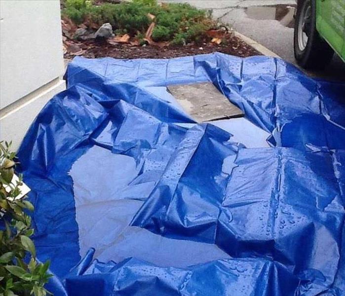 tarp covered with rain water on ground outside building